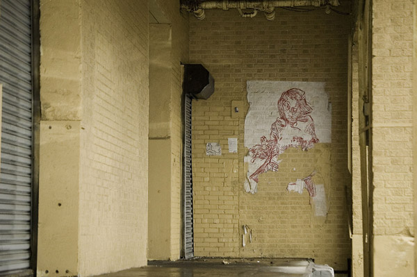 A street-art poster hangs outside a loading dock, amid
yellow bricks.