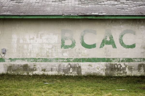 Green block letters, on a cinder block wall, read
BCAC.