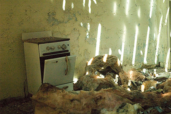 An old stove sits in insulation and shafts of
sunlight.