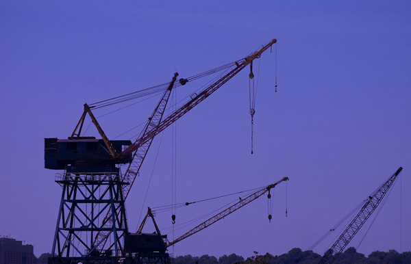 Several dock cranes are in silhouette against a dark blue
sky.