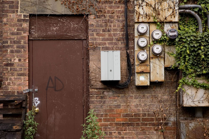 A rusting iron door, electric meters, and ivy.