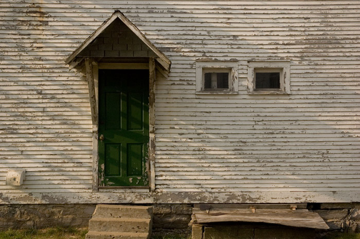 A weathered, wood building with a door, awning, and windows.