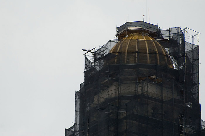 A building's dome is hidden by scaffolding and sheets.
