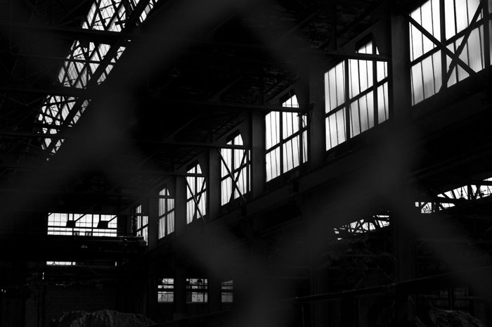 The interior of a darkened factory lets light in from windows.