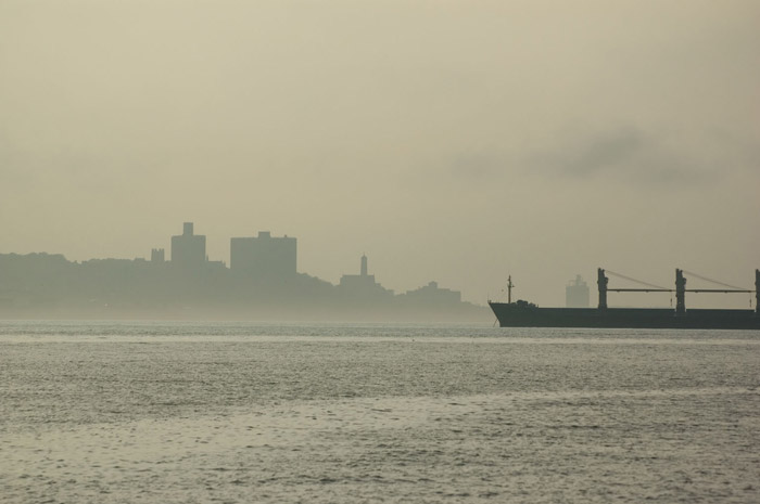 A ship's silhouette, against high-rise buildings.