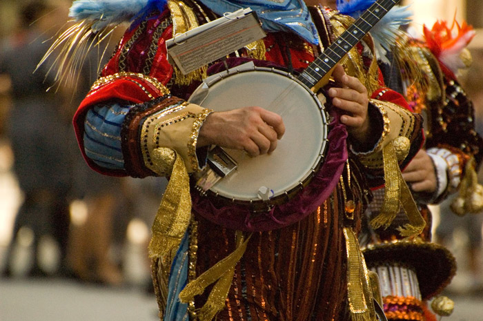 A banjo player, in colorful costume, waits to march.