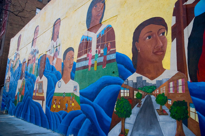 A mural shows women of various races, in different neighborhood activities.