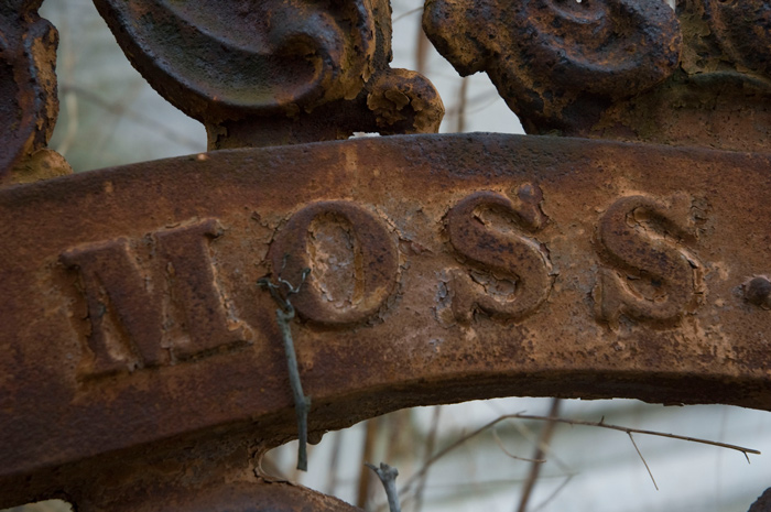 The top of a rusted gate, with the family name.