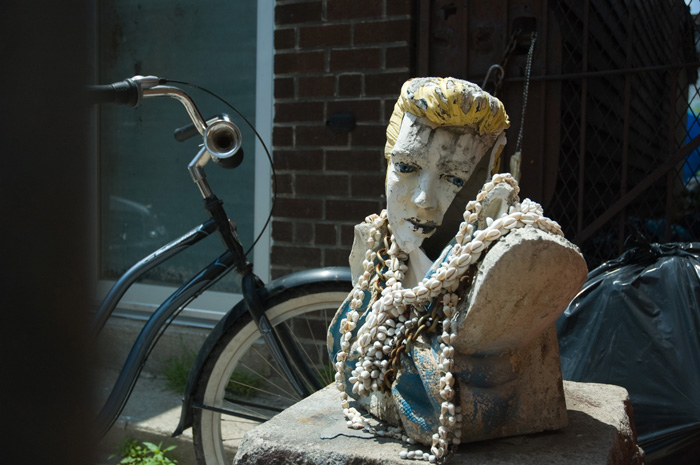 A bust of an Elvis-like figure (but with yellow hair) has been draped with several necklaces made of sea shells.