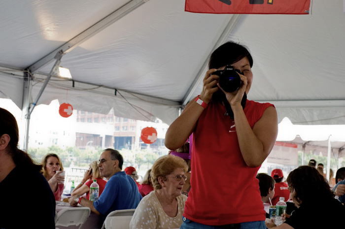 At a celebration of Swiss National Day, a freelance photographer in a red top takes pictures of partiers.