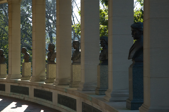 The many columns of a colonnade are separated with busts of great Americans; sunlights streams through.