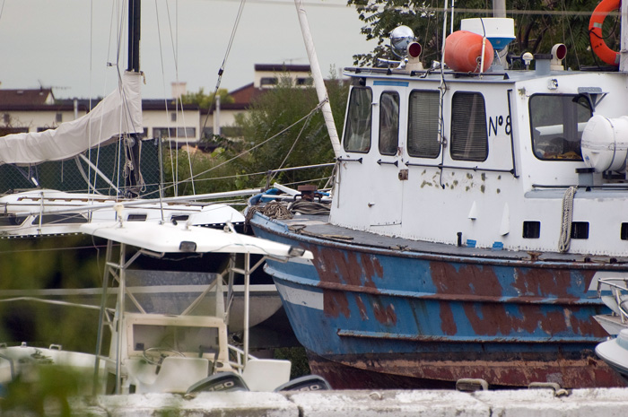 An old blue and white yacht, painted with the name 'No. 8,' sits in a boatyard dock.