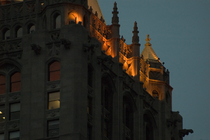 A gargoyle juts out from a building in silhouette.