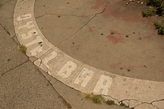 A piece of sidewalk on an empty lot says 'Oyster Bar,' suggesting a long gone restaurant.