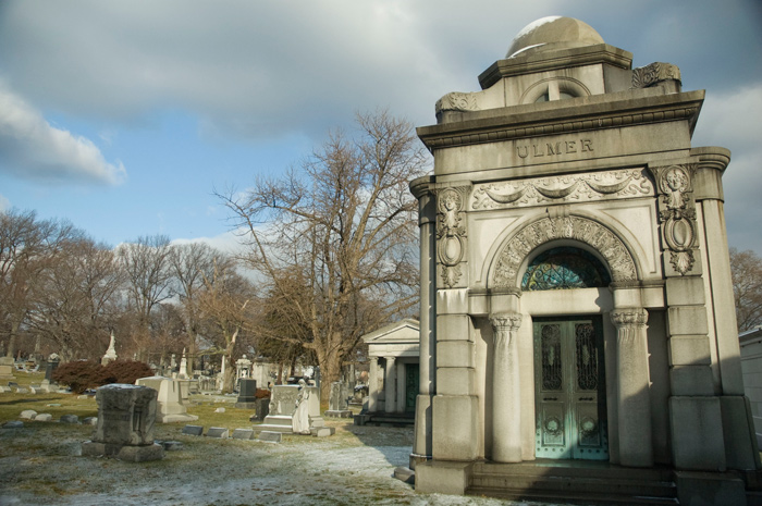 An ornate mausoleum stands out amid its surroundings; all show signs of snowfall.