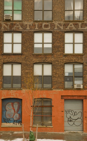 Above the windows of a brick building, part of an old company's painted name, 'National,' remains.