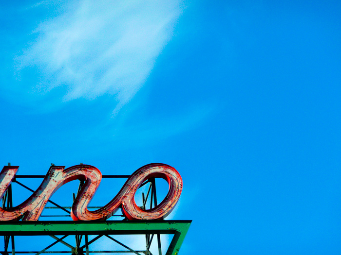A detail of a neon sign, reading 'No,' stands out against a blue sky.