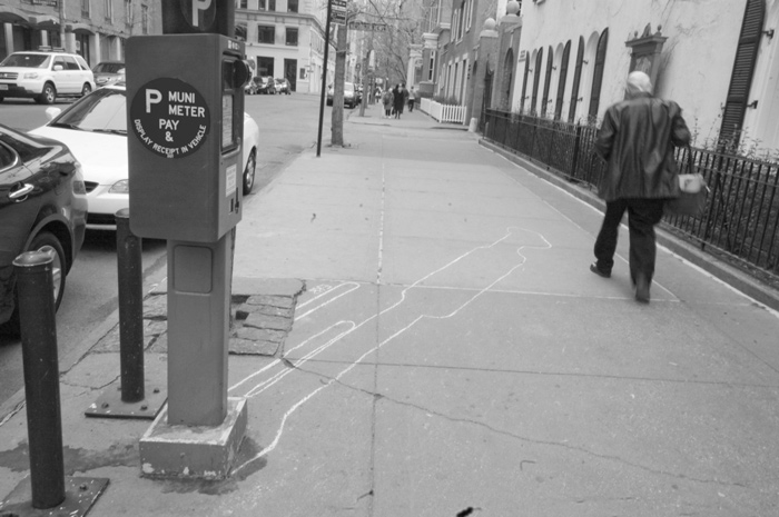 A man walks on a sidewalk where an artist has outlined the former shadows of poles and parking meters.