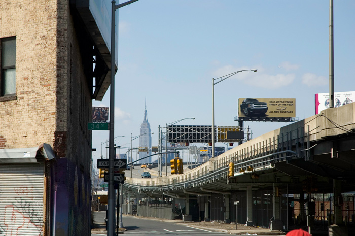 The Empire State Building is seen in the distance, beyond an expressway.