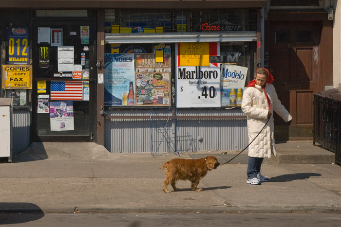 A woman commands her dog to continue walking with her.