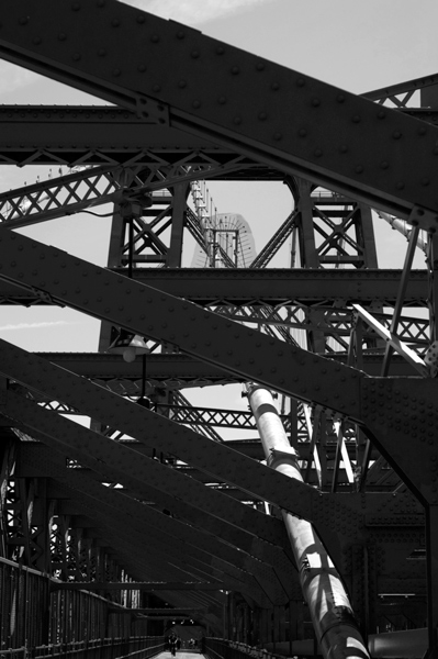 The criss-cross metal structure of a bridge, in silhouette.