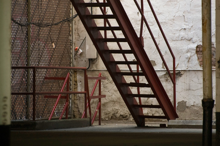 Two metal staircases meet amid old walls in a parking garage.