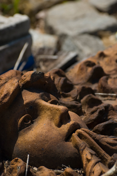 A face of molded terra cotta lies among debris.