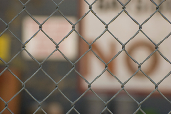 The word 'No' is seen through a chain-link fence.