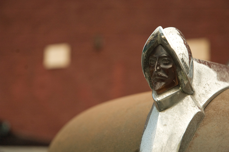 A helmeted bust of Hernando De Soto sits, in chrome, on top of a car hood.