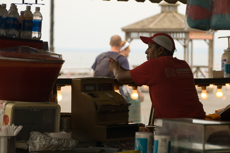 An employee at a fast food counter on Coney Island's boardwalk watches the sparse traffic pass by after the season.