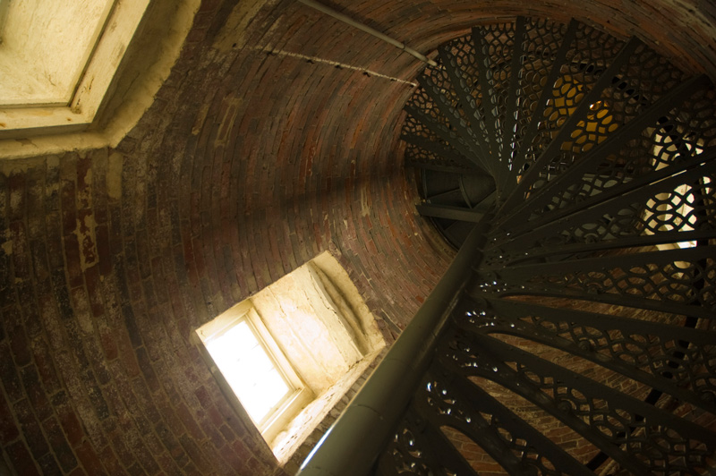 A spiral staircase twists up the brick tower of a lighthouse.