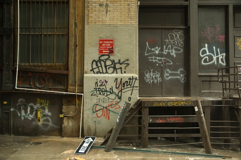 Graffiti covers the walls, doors, and steps leading to a freight entrance.