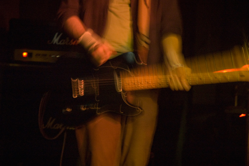 Photo showing a rock guitarist's torso and fore arms, playing the guitar.