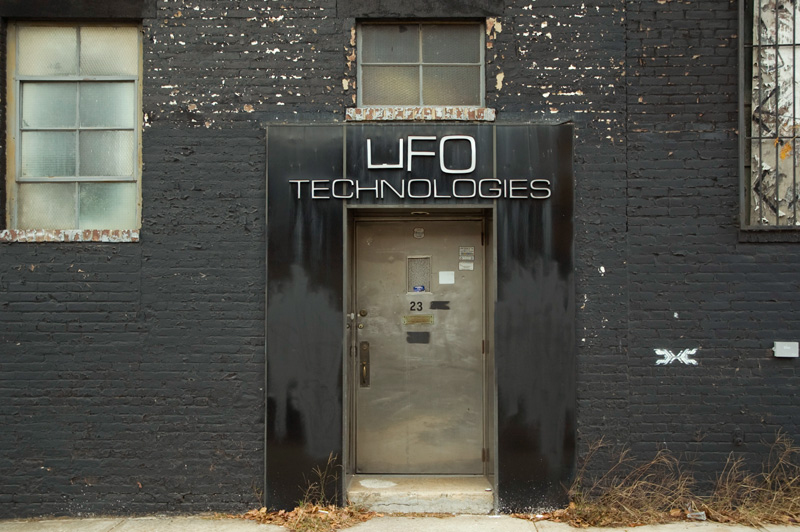 A black brick building with a stainless steel door, labeled 'UFO Technologies.'