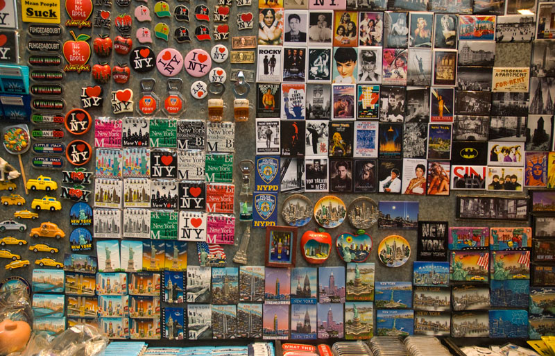 A board is filled with a wide variety of souvenir refrigerator magnets.
