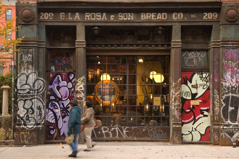 An antiques store in an old baker's storefront, with graffiti on surrounding walls.