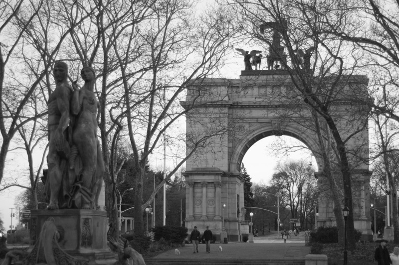 Two tall statues, barren winter trees, and a memorial arch.