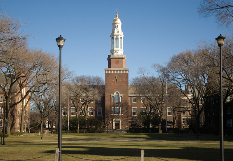 A white cupola rises above a brick building standing on a quad.