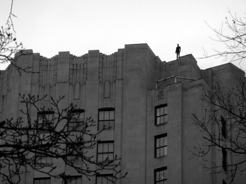 A statue of a man, atop a very tall building.