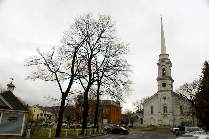 A tall steeple on a white church rises well above all its surroundings.