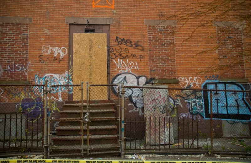 A fenced-off brick building covered with graffiti.
