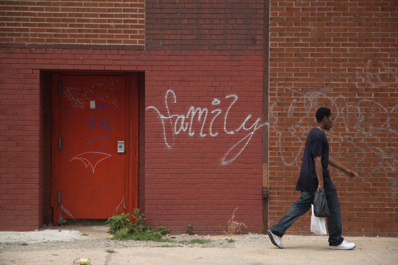A man walks past a graffiti reading 'family.'