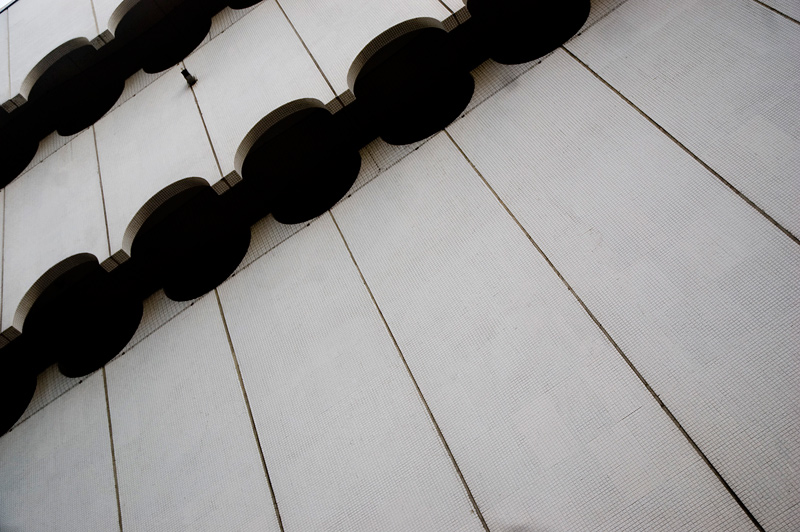 Cut-outs in a building façade form black circles.