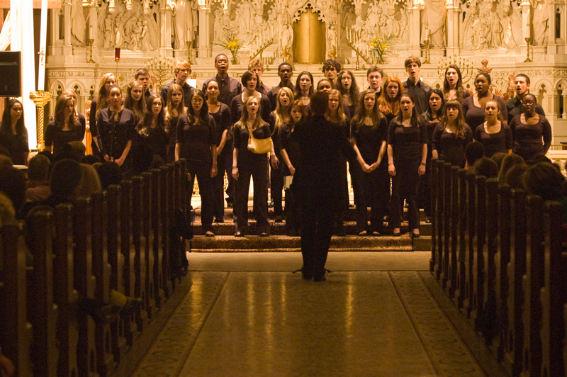 A school choir sings in front of a church altar, conducted by Matthew Brady.