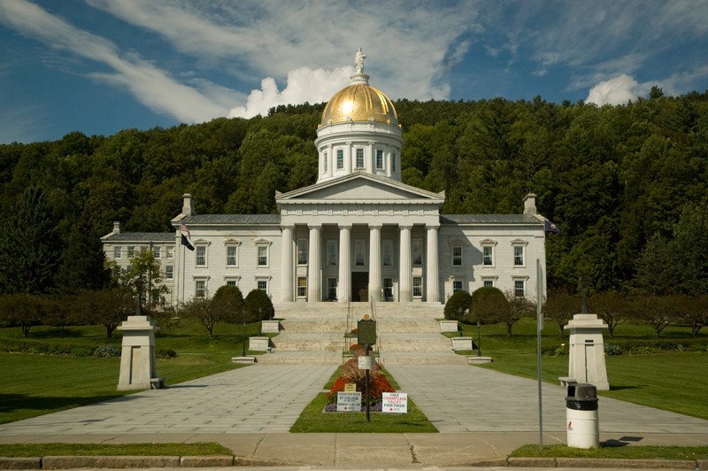 A statue atop a golden dome on a classical building with columns.