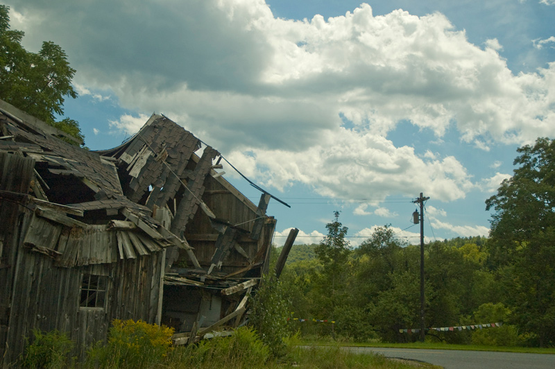 A roadside shack, with the roof collapsed.