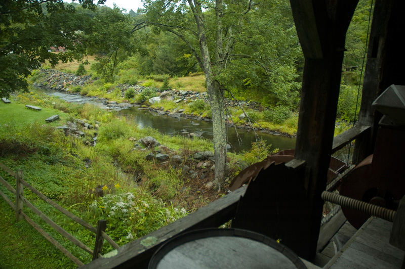 A creek flows between greenery and rocks, seen from a porch.