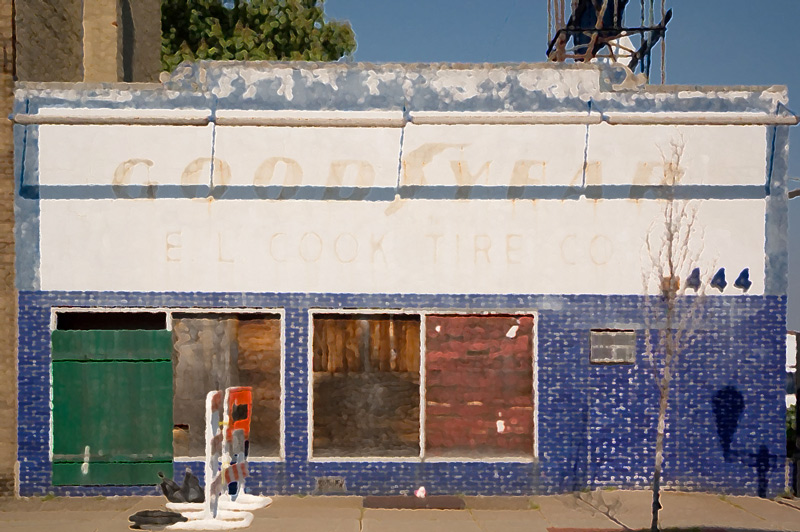A boarded-up store front, with faded letters for Goodyear tires.