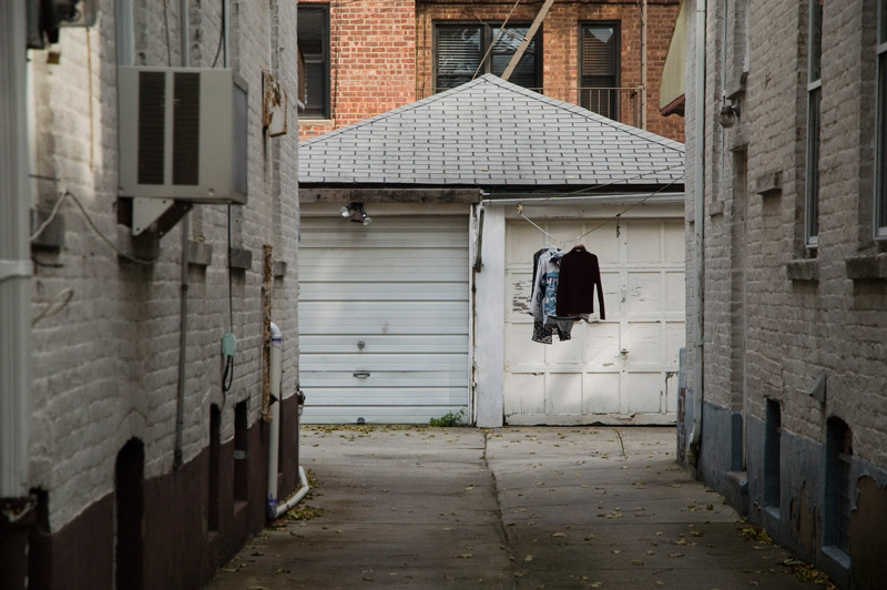Clothes on a clothes line, suspended between a building and a garage.