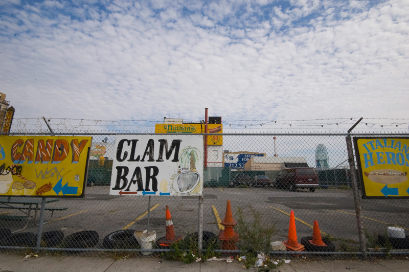 Colorful, hand-painted signs on a fence point to clam bar.